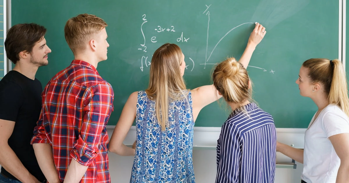 Schülerinnen und Schüler lösen Aufgabe an Tafel im Klassenzimmer