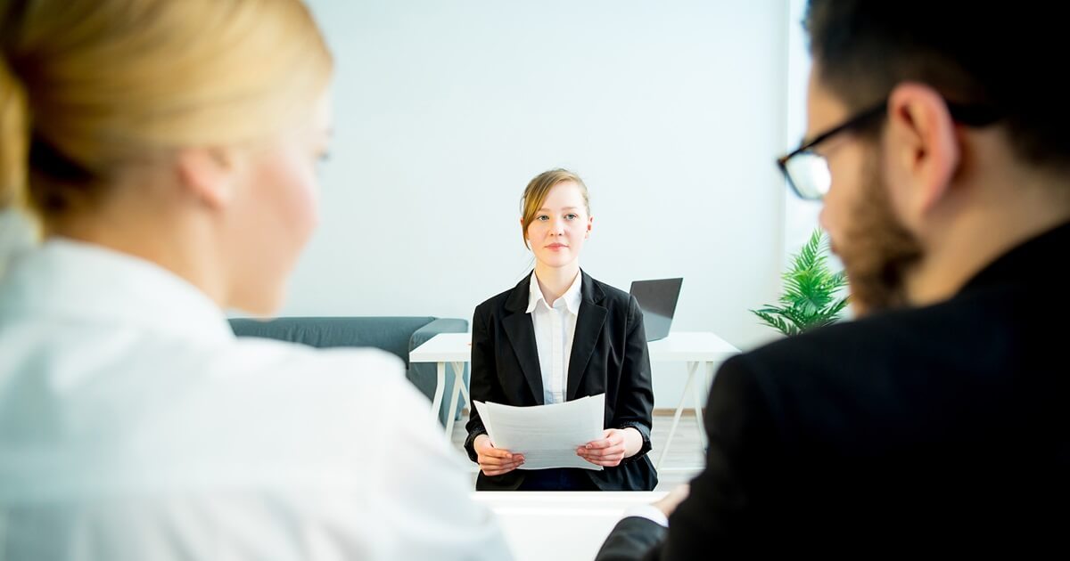 Junge Frau stellt sich im Vorstellungsgespräch den Recruitern vor